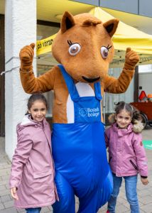 Bostadsbolagets maskot Reture i mitten med två små barn vid sidan av sig. 