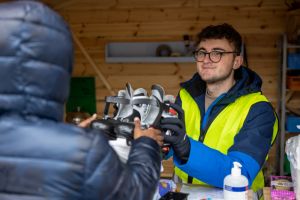 En kille i arbetskläder lämnar ut skridskor från en kiosk.