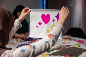 En flicka håller upp ett tygstycke med tryckta hjärtan på.