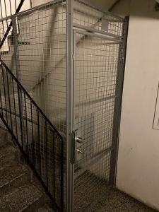 Bilden föreställer en gallerbur med dörr som leder ner till källarförråd.